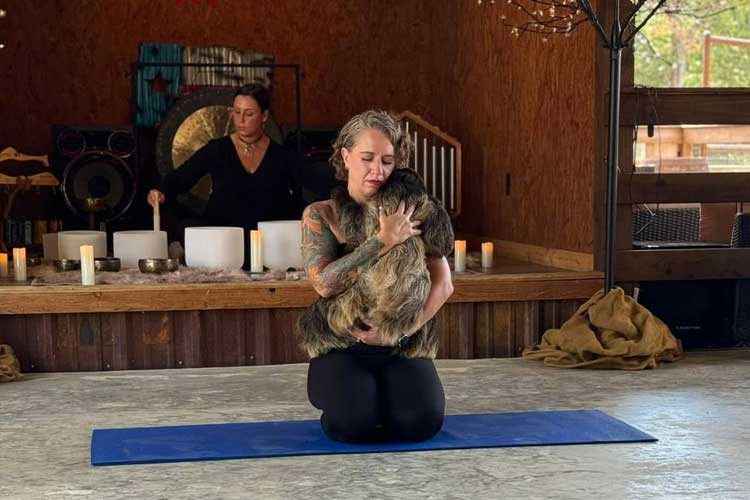 Woman sound bathing while holding a sloth
