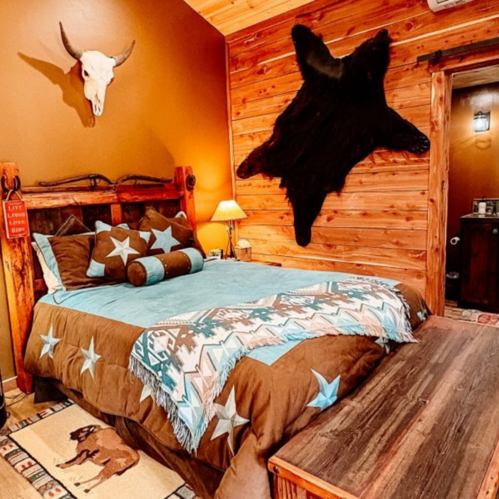 A luxurious ranch lodge bedroom featuring rustic decor and a large window looking out onto a landscape.